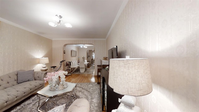 living area with ornamental molding, arched walkways, and wood finished floors