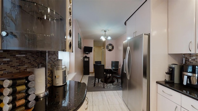 kitchen featuring backsplash, a notable chandelier, stainless steel fridge, and white cabinets