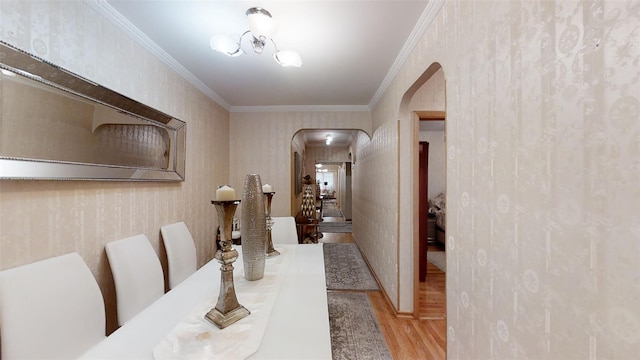 hall with ornamental molding, wood finished floors, and arched walkways