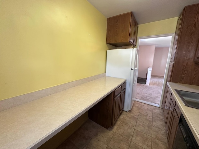 kitchen with freestanding refrigerator, dishwasher, light countertops, and a sink