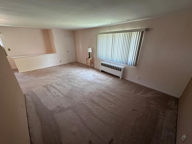 unfurnished living room with radiator heating unit and carpet