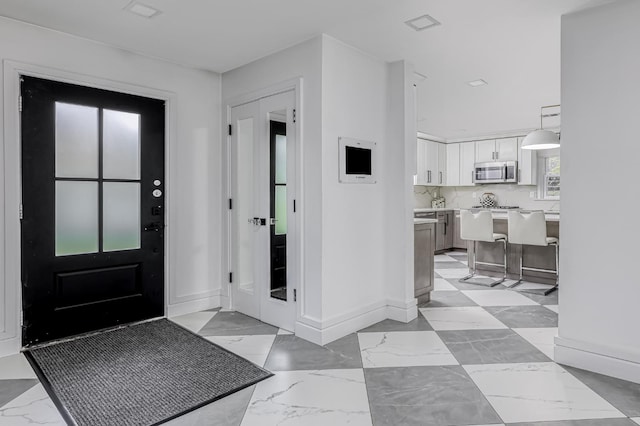 entrance foyer with baseboards and marble finish floor