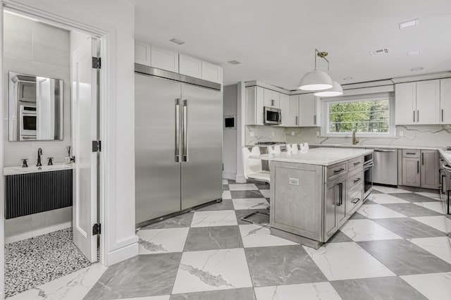 kitchen with appliances with stainless steel finishes, light countertops, a kitchen island, and decorative backsplash