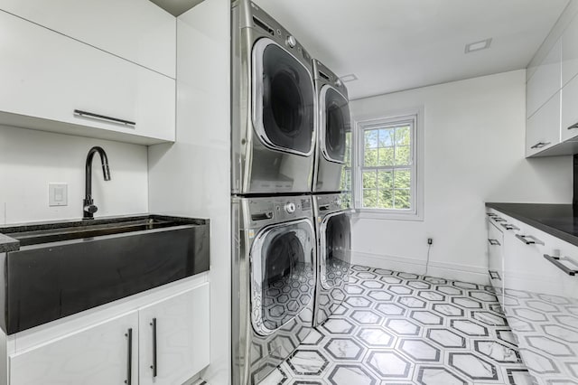 laundry room featuring stacked washing machine and dryer, cabinet space, and baseboards