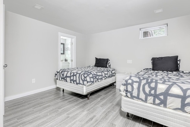 bedroom featuring light wood-style flooring, baseboards, and connected bathroom