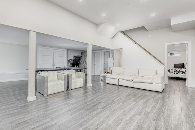 living area with light wood-type flooring, baseboards, and an office area