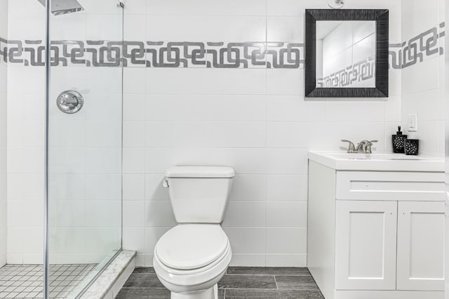 full bathroom with tile walls, a shower stall, toilet, and vanity