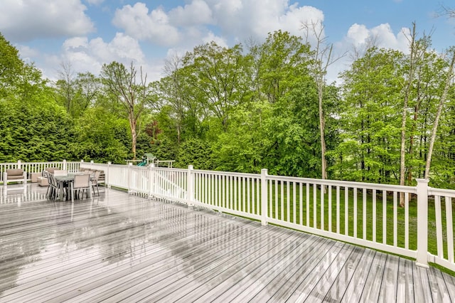 deck featuring outdoor dining space and a lawn
