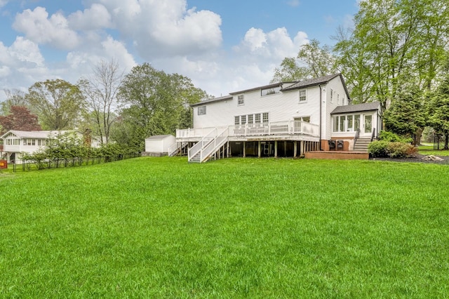 rear view of house featuring stairway, a wooden deck, a sunroom, and a yard