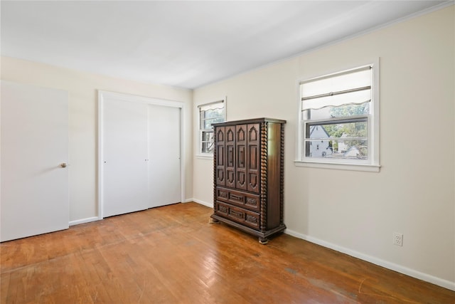 31 Westwood Ave, New Rochelle, NY 10801 - unfurnished bedroom with multiple windows, wood finished floors, a closet, baseboards, and crown molding