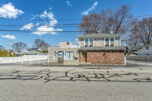 view of front facade with brick siding and fence
