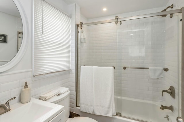 full bath featuring a sink, toilet, and bath / shower combo with glass door