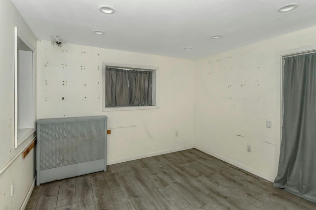 unfurnished room with recessed lighting, wood finished floors, and radiator heating unit