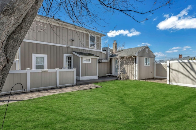 back of property featuring a yard, an outbuilding, and a fenced backyard