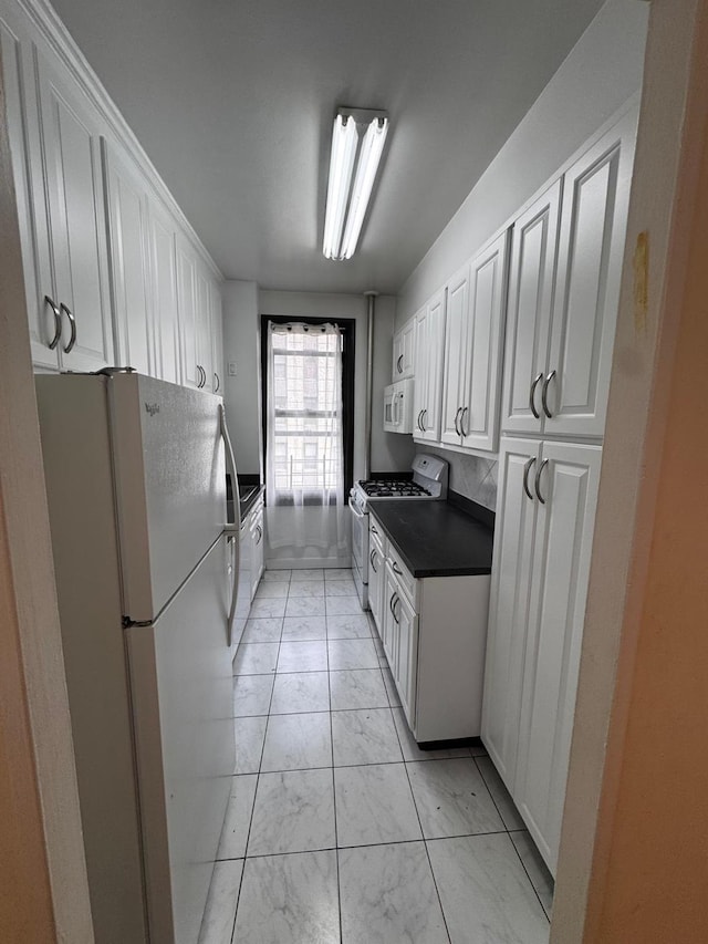 9825 64th Rd Unit 5F, Rego Park, NY 11374 - kitchen featuring white appliances, dark countertops, white cabinets, and light marble finish floors