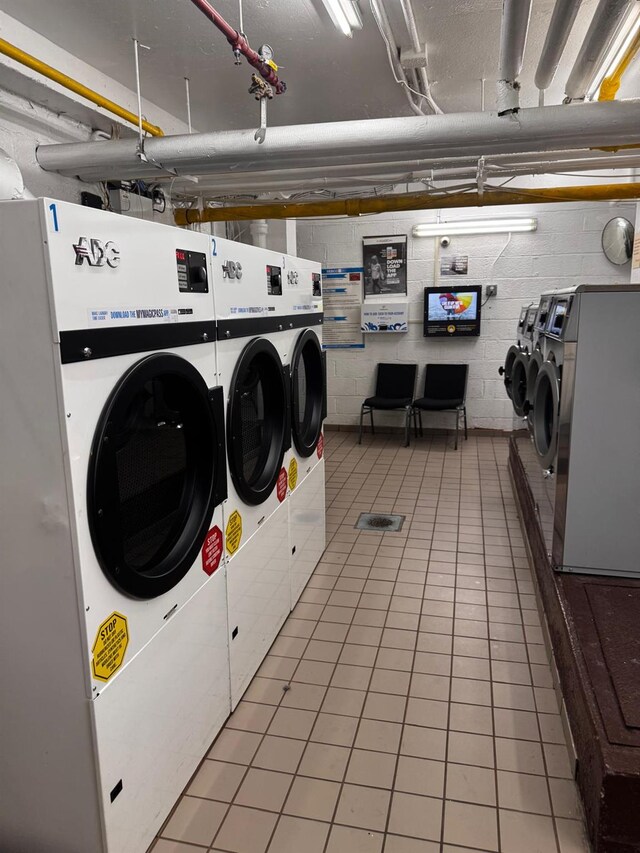 9825 64th Rd Unit 5F, Rego Park, NY 11374 - community laundry featuring washer and clothes dryer, light tile patterned floors, and concrete block wall