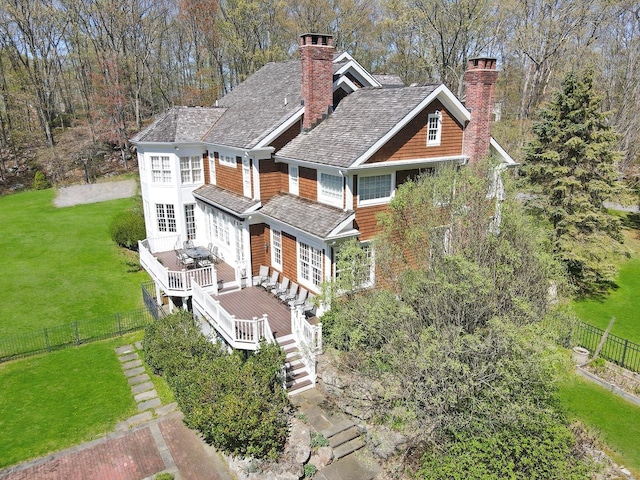 back of property with a yard, a chimney, a deck, and a fenced backyard