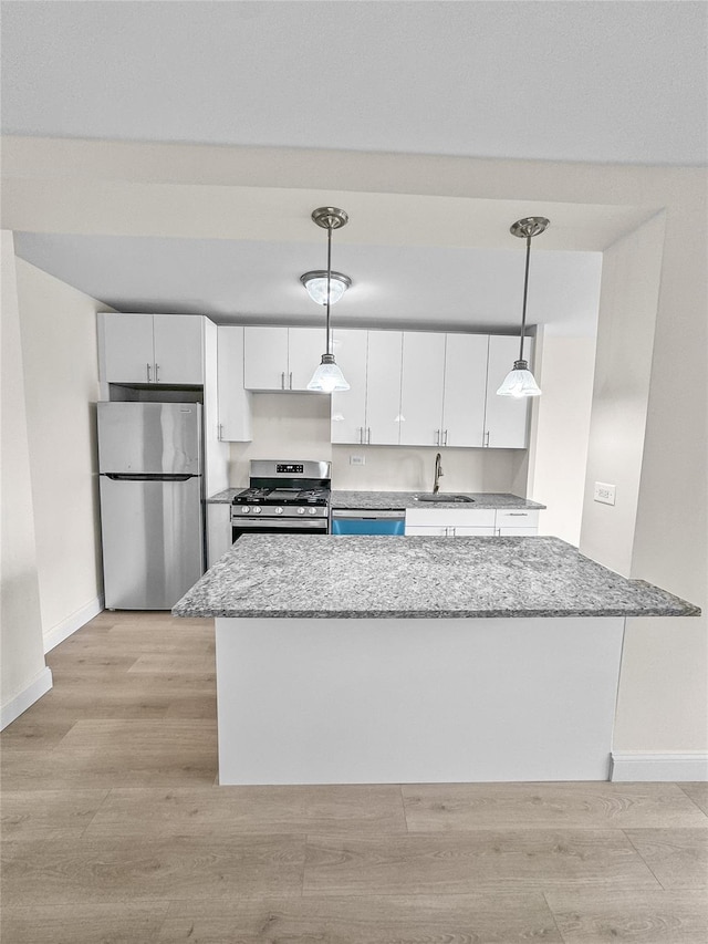 kitchen featuring a sink, stainless steel appliances, light wood-type flooring, white cabinetry, and baseboards