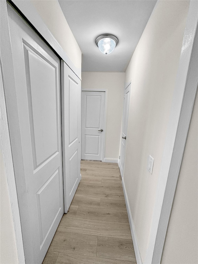 hall with light wood finished floors and baseboards
