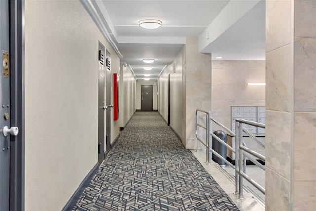 hallway featuring carpet flooring, baseboards, and mail area