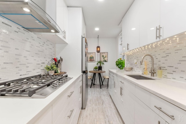 kitchen with a sink, under cabinet range hood, stainless steel gas cooktop, tasteful backsplash, and recessed lighting