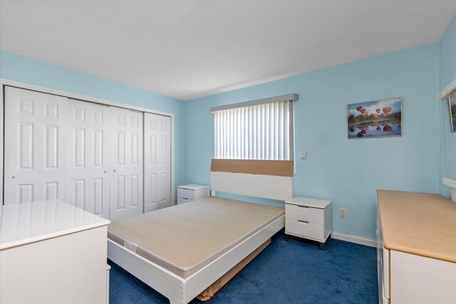 bedroom featuring a closet, dark colored carpet, and baseboards
