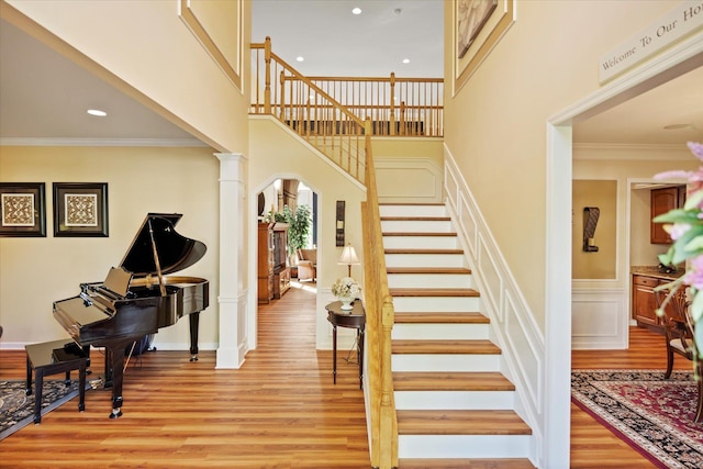 7 Moreland Ct, Mount Sinai, NY 11766 - stairway featuring ornate columns, wood finished floors, wainscoting, arched walkways, and ornamental molding