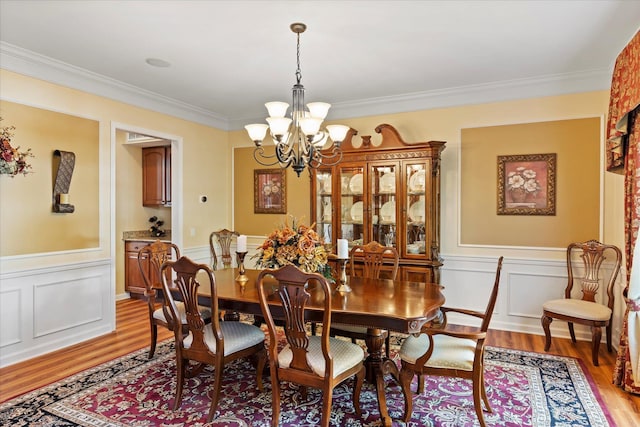 7 Moreland Ct, Mount Sinai, NY 11766 - dining room featuring a chandelier, light wood-type flooring, crown molding, wainscoting, and a decorative wall