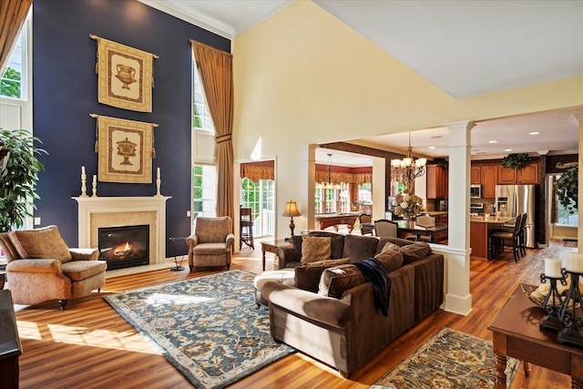 7 Moreland Ct, Mount Sinai, NY 11766 - living room featuring decorative columns, a chandelier, wood finished floors, a glass covered fireplace, and plenty of natural light