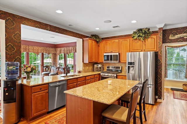 7 Moreland Ct, Mount Sinai, NY 11766 - kitchen featuring stainless steel appliances, wallpapered walls, light stone countertops, a sink, and light wood-style floors