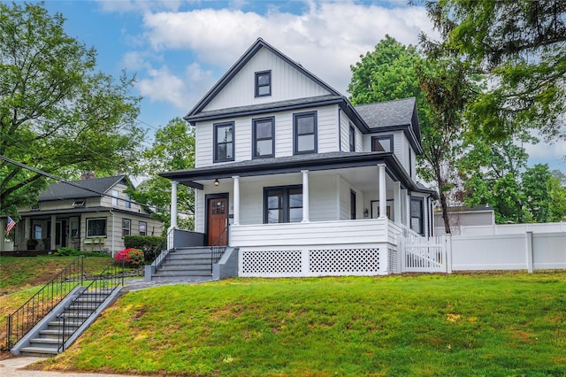view of front of house featuring a front lawn, a porch, stairway, and fence