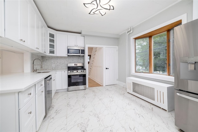 kitchen with a sink, light countertops, appliances with stainless steel finishes, tasteful backsplash, and radiator heating unit