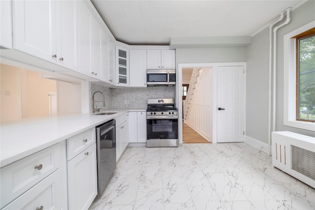 kitchen with a sink, radiator heating unit, backsplash, light countertops, and appliances with stainless steel finishes