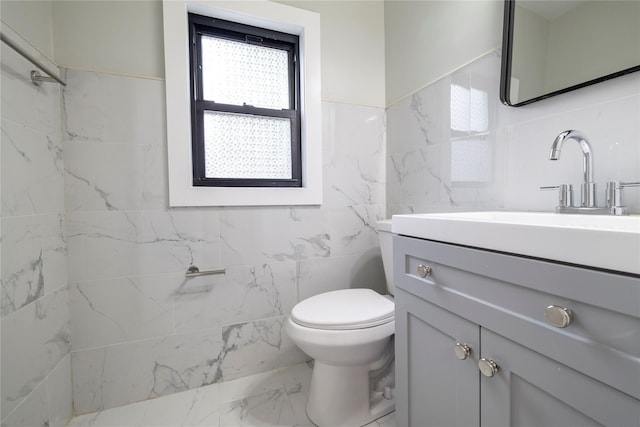 bathroom with tile walls, toilet, marble finish floor, vanity, and a shower