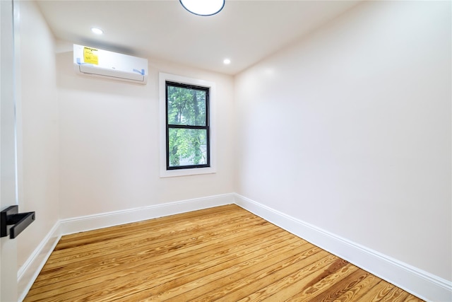 unfurnished room featuring light wood-style flooring, an AC wall unit, baseboards, and recessed lighting