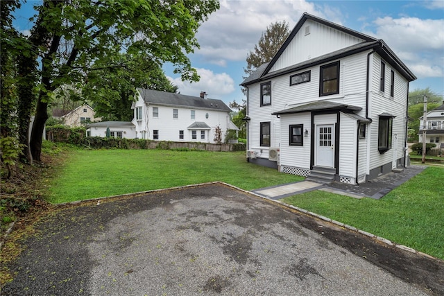view of front of home featuring a front lawn, board and batten siding, fence, and entry steps