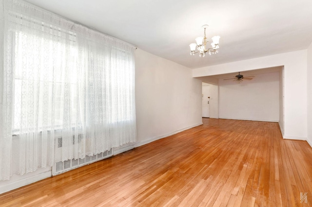 spare room with a chandelier, radiator heating unit, hardwood / wood-style floors, and baseboards