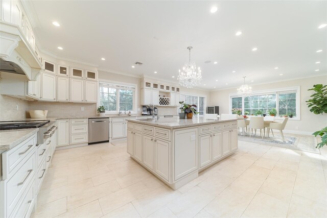 kitchen featuring a chandelier, appliances with stainless steel finishes, decorative backsplash, a sink, and an island with sink
