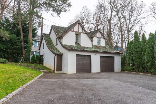 view of front of home with stucco siding, driveway, a garage, and a front yard
