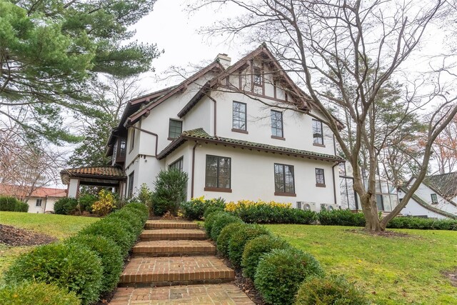 view of front of home featuring stucco siding, a chimney, and a front lawn