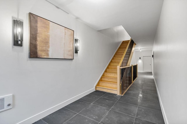 hallway with baseboards, stairway, and dark tile patterned floors