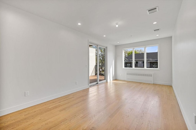 empty room featuring radiator, light wood-style floors, baseboards, and recessed lighting