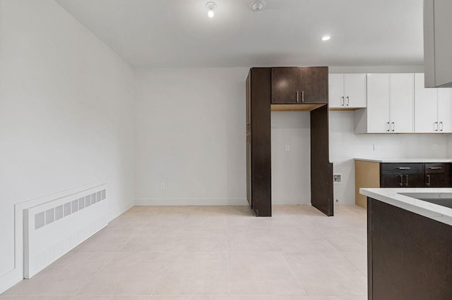 kitchen with radiator heating unit, light countertops, white cabinets, dark brown cabinets, and recessed lighting