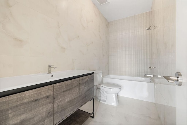 bathroom featuring tile walls, toilet, washtub / shower combination, vanity, and marble finish floors