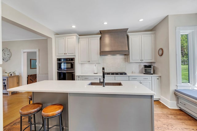 80 Hill St, Walden, NY 12586 - kitchen with premium range hood, a sink, a kitchen breakfast bar, light wood-type flooring, and decorative backsplash