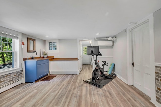 80 Hill St, Walden, NY 12586 - workout area with baseboard heating, a wall unit AC, baseboards, light wood finished floors, and a sink
