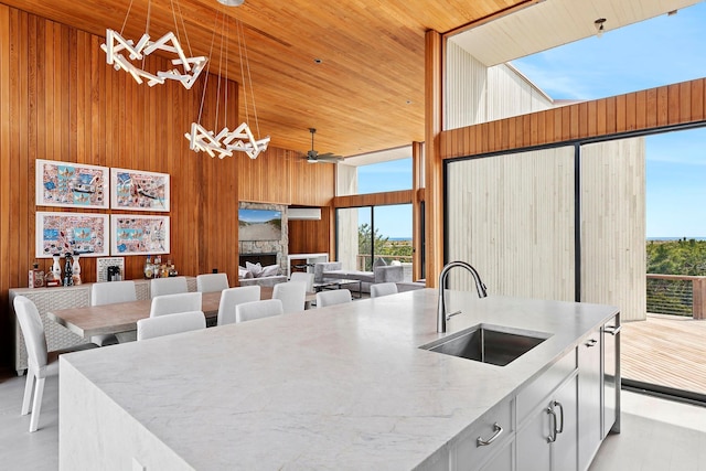 199 Dune Rd, Westhampton Beach, NY 11978 - kitchen featuring pendant lighting, ceiling fan, a sink, wooden walls, and high vaulted ceiling