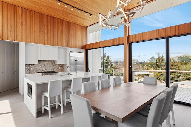 199 Dune Rd, Westhampton Beach, NY 11978 - dining room with wooden ceiling, rail lighting, a chandelier, a towering ceiling, and light wood-style floors