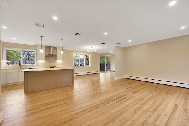 kitchen with wall chimney range hood, light wood-type flooring, baseboard heating, open floor plan, and light countertops