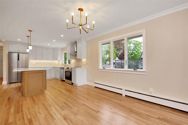 kitchen with appliances with stainless steel finishes, wall chimney range hood, plenty of natural light, crown molding, and a center island